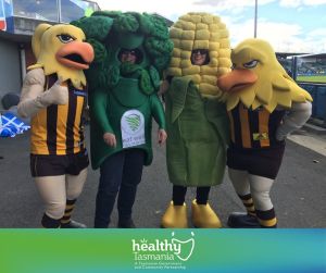 Postcard showing Hawkes player, person in broccoli costume, person in corn costume and person dressed up as Hawk mascot